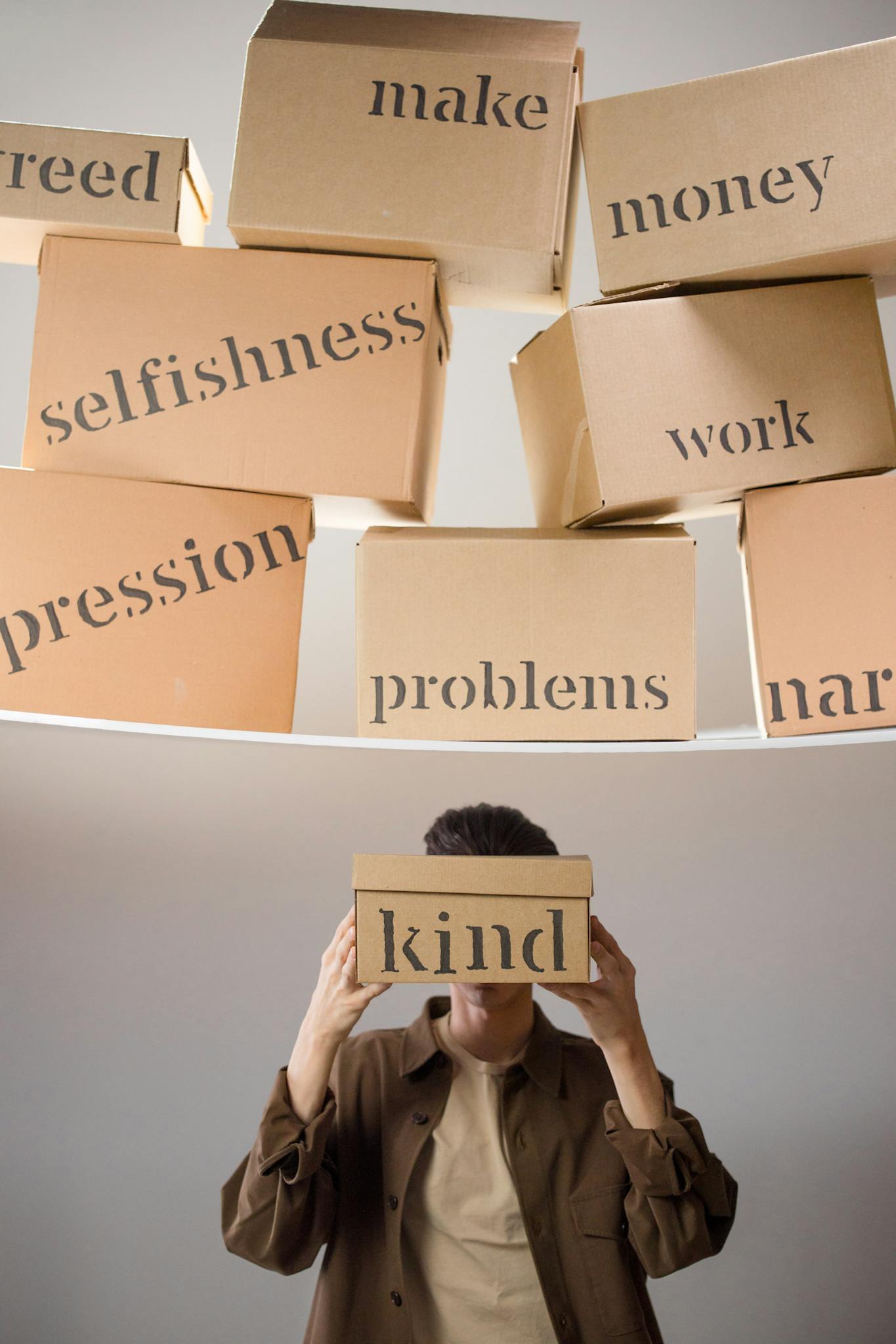 A person holds a box labeled 'kind' amidst a backdrop of issues like greed and problems.