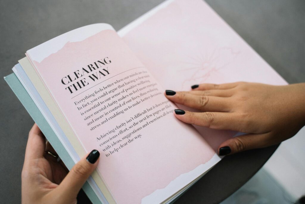 Hands flipping through a motivational book indoors, promoting clarity and wisdom.